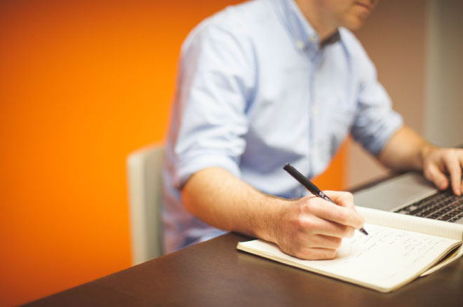 Person with their computer and a notebook, ready to see strategy instead of routine.