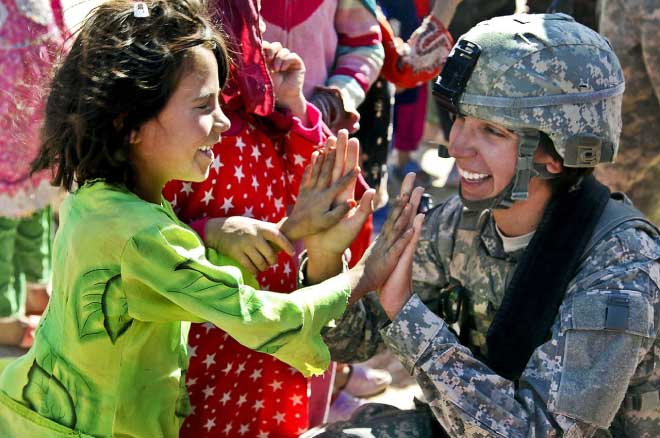 Woman soldier in uniform having a happy interaction with a child.